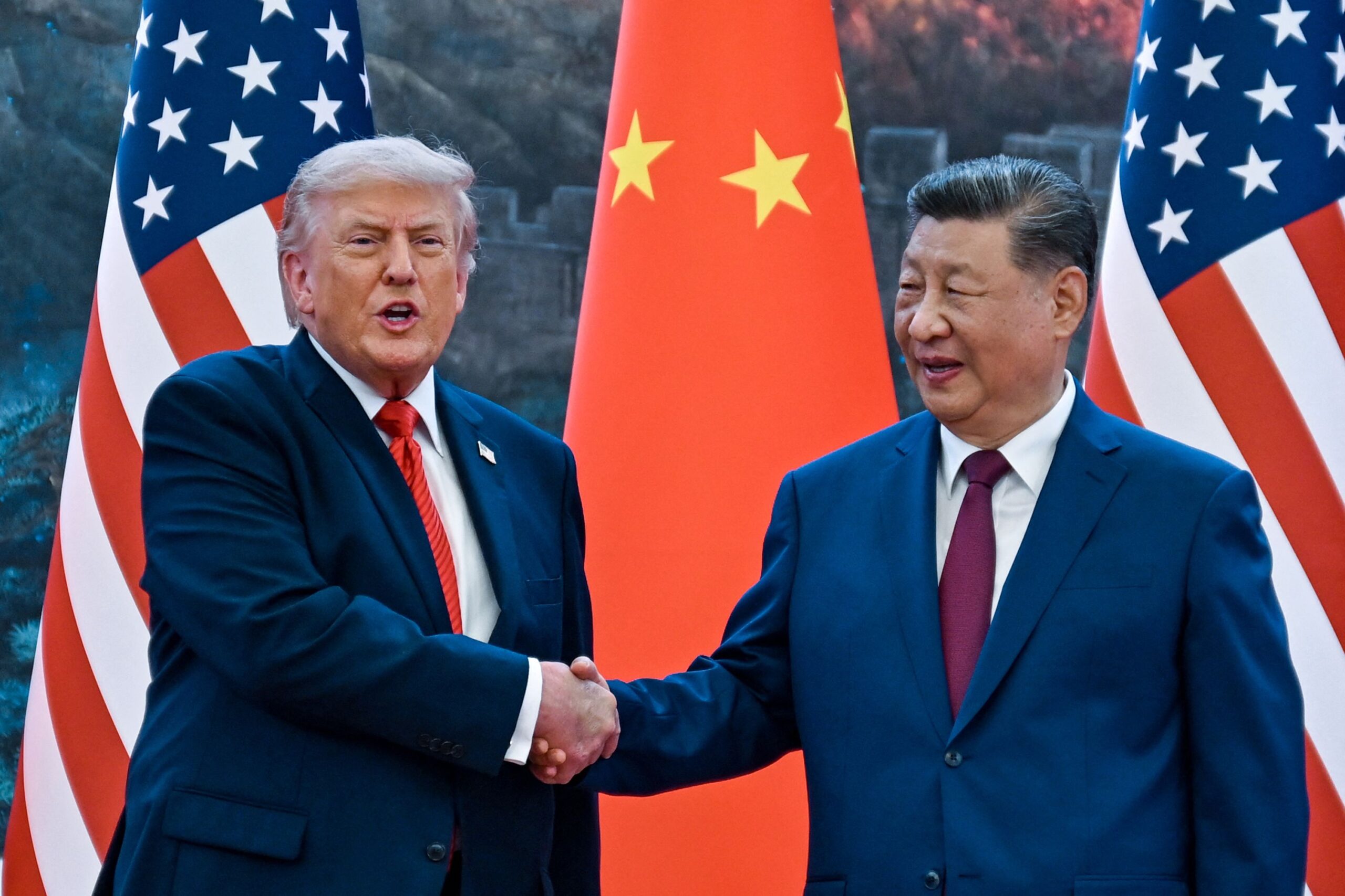 Donald Trump and Xi Jinping standing before military honor guards in Beijing amid tensions over Taiwan, Iran, and rare earth trade.